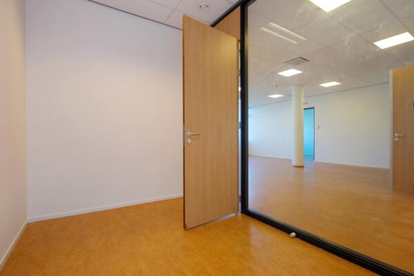Leeg kantoorpand aan de Harriet Freezerhof met open houten deur en glazen tussenwand.
